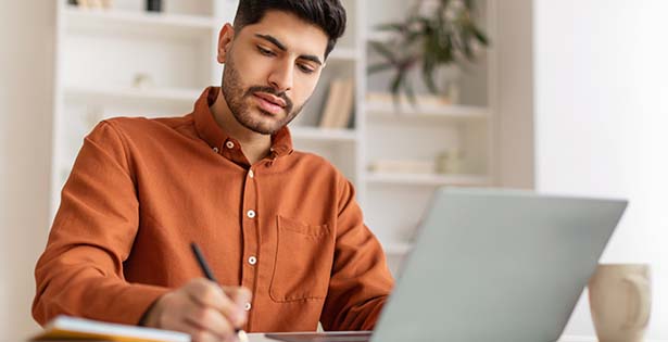 Student studying online while taking notes.