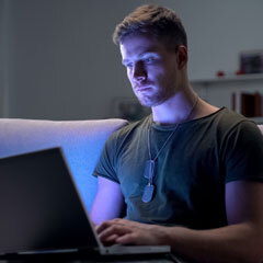 Military guy studying on laptop at night