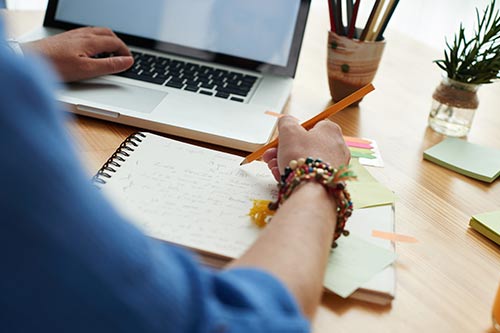 person working with pencil, notebook and laptop