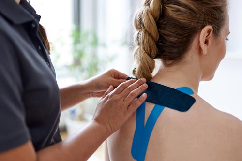 Athletic tape is applied to a person's back by a trainer or therapist.