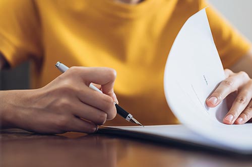 a hand holding a pen flipping through papers