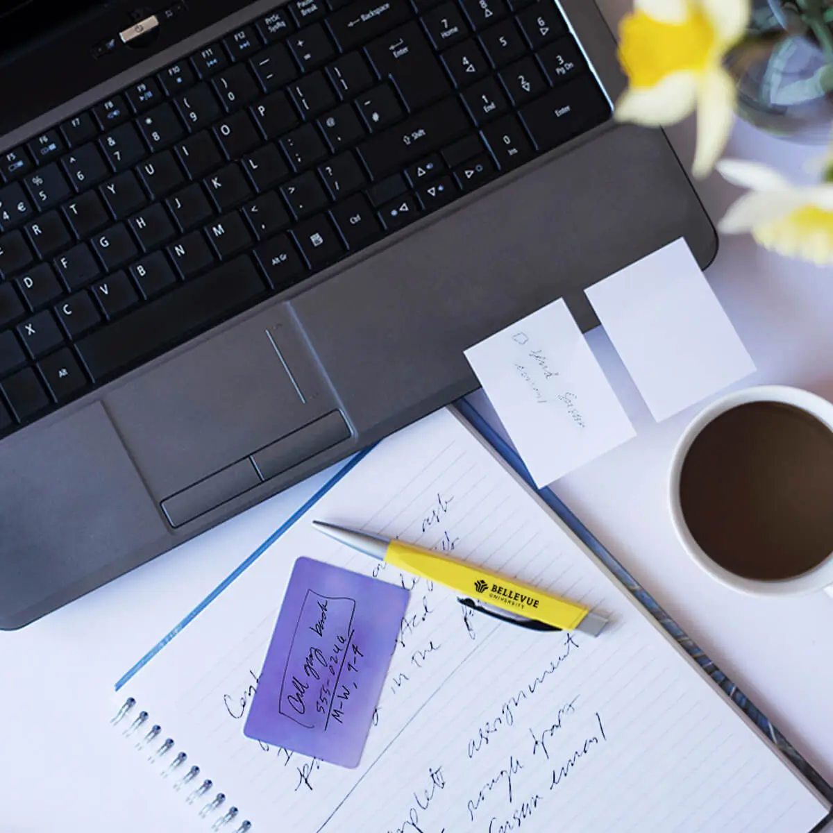 a cup of coffee and papers next to a laptop