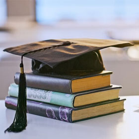 stack of books with graduation cap